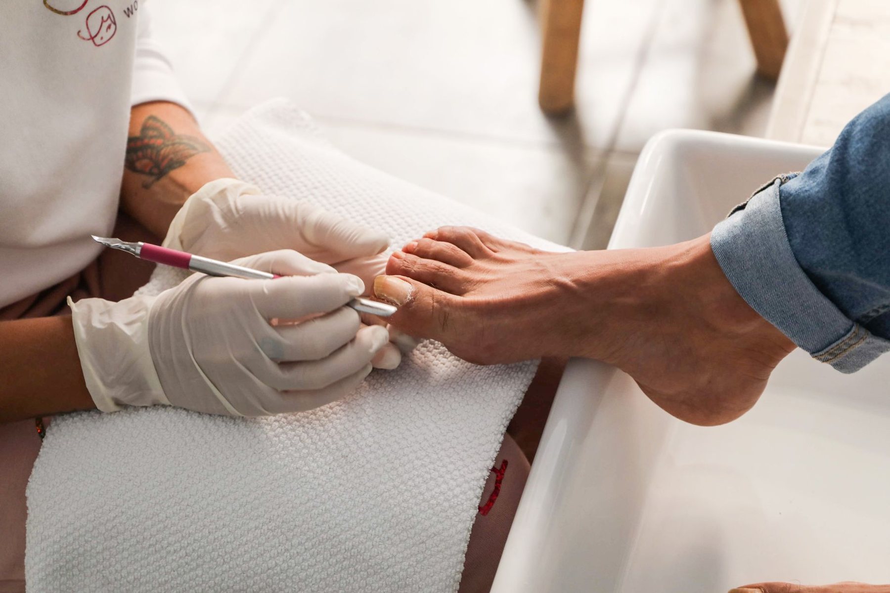 Podóloga con guantes tratando el pie de un paciente